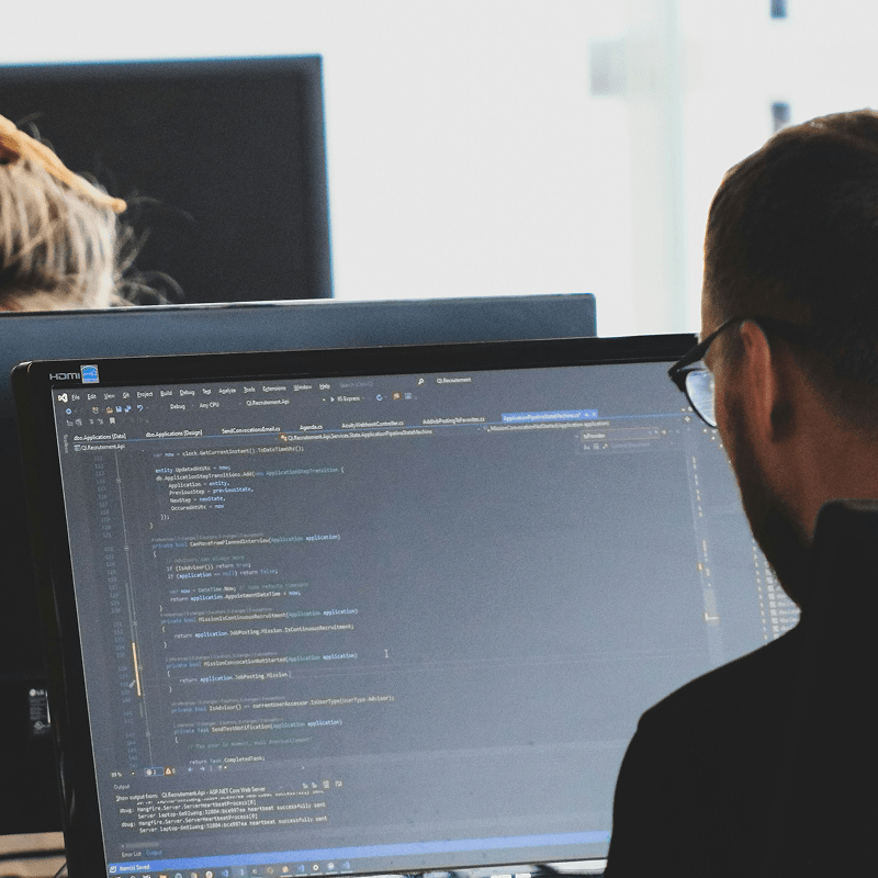 Entwickler arbeitet am Computer mit Code auf dem Bildschirm