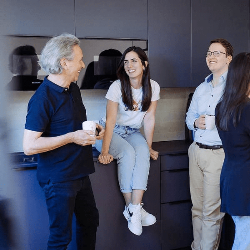 Vier mindtwo Teammitglieder unterhalten sich locker in der B&uuml;rok&uuml;che, zwei mit Kaffeetassen, eine Person sitzt auf der Arbeitsplatte